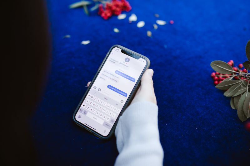 スマートフォンでメッセージのやり取りを確認している手元
